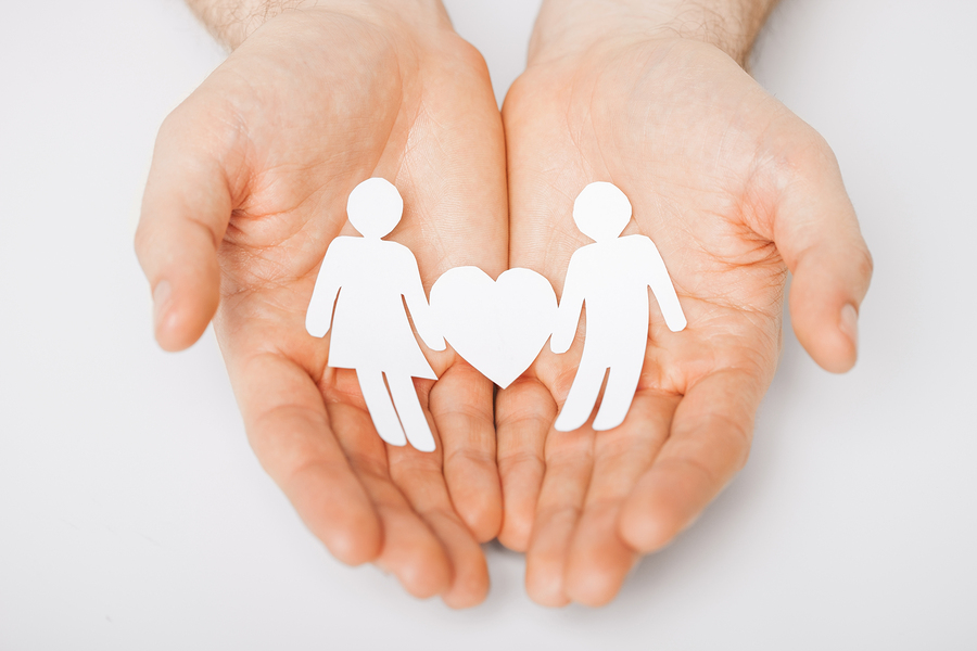 man hands showing two paper men with heart shape